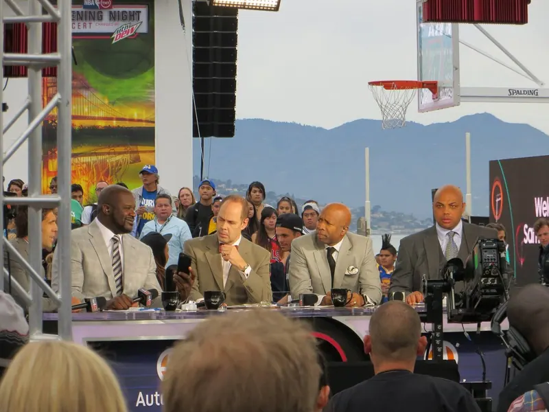 TNT's Inside the NBA crew at an outdoor desk on NBA opening night 2015; left to right: Shaquille O'Neal, Ernie Johnson, Kenny Smith and Charles Barkley.
