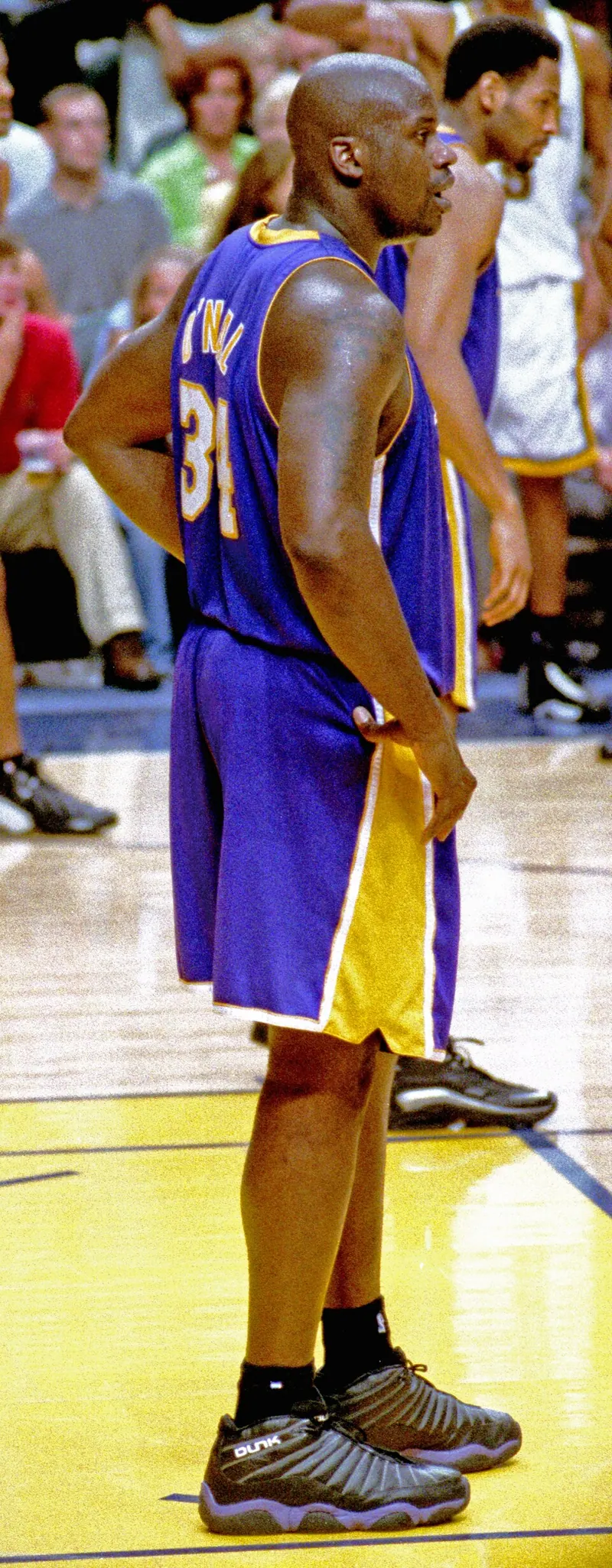 Shaquille O'Neal in a purple Lakers #34 road uniform stands on court during Game 5 of the 2000 NBA Finals against the Indiana Pacers (film scan, side/back view).