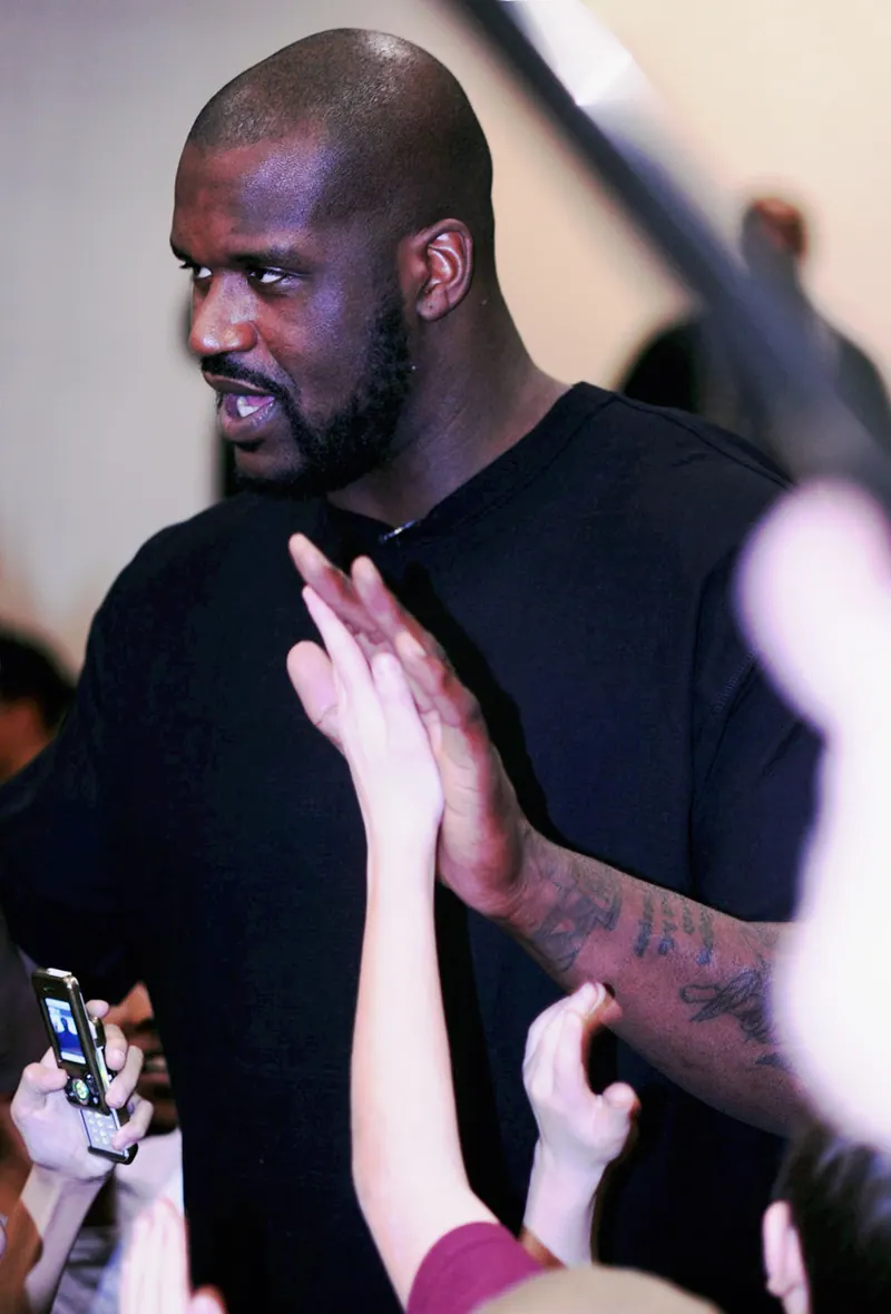 Shaquille O'Neal, in a black T-shirt, high-fives a crowd of Airmen and families during a visit to Buckley Air Force Base, Colorado.